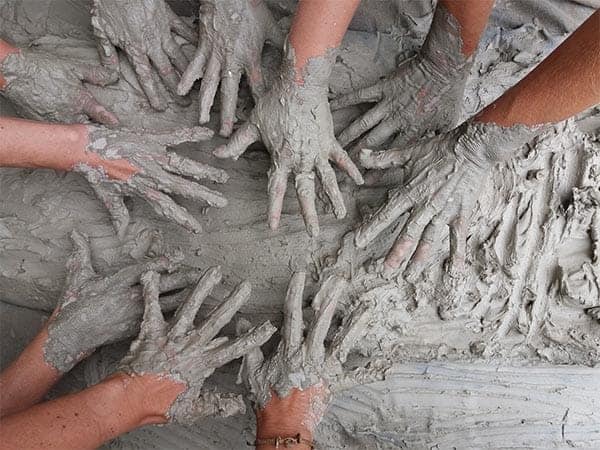 Big Ditch Dam Builder people with wet clay on their hands