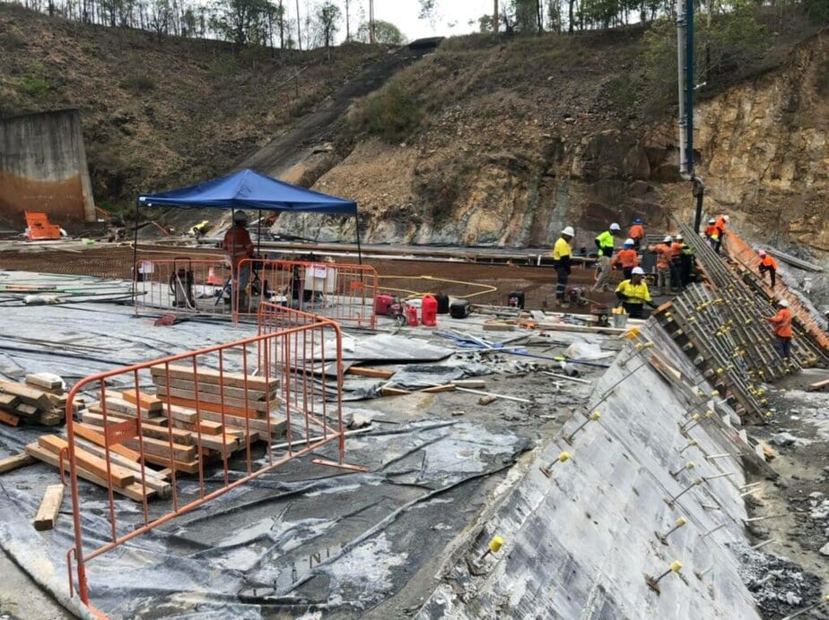 Dam construction with workers and equipment in progress.