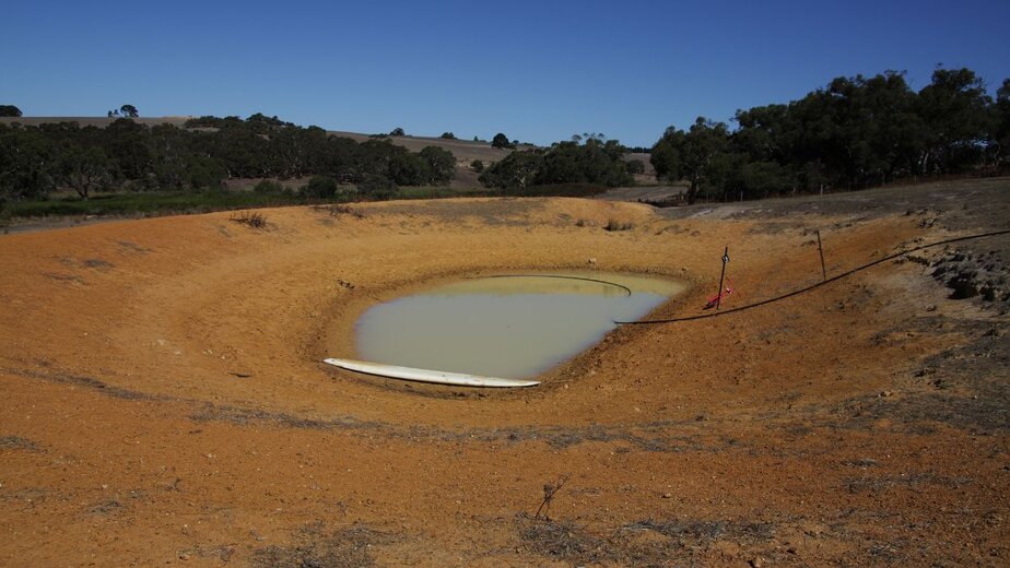 Dam construction site with water reservoir and earthworks by Big Ditch Dam Building Company.