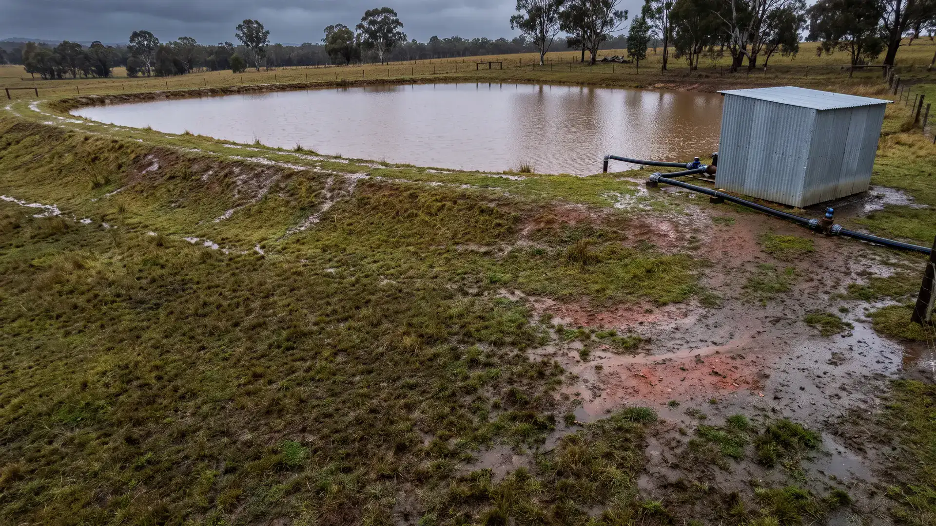 Australian dam and pump shelter after rain, illustrating separate assets to check for farm dam insurance