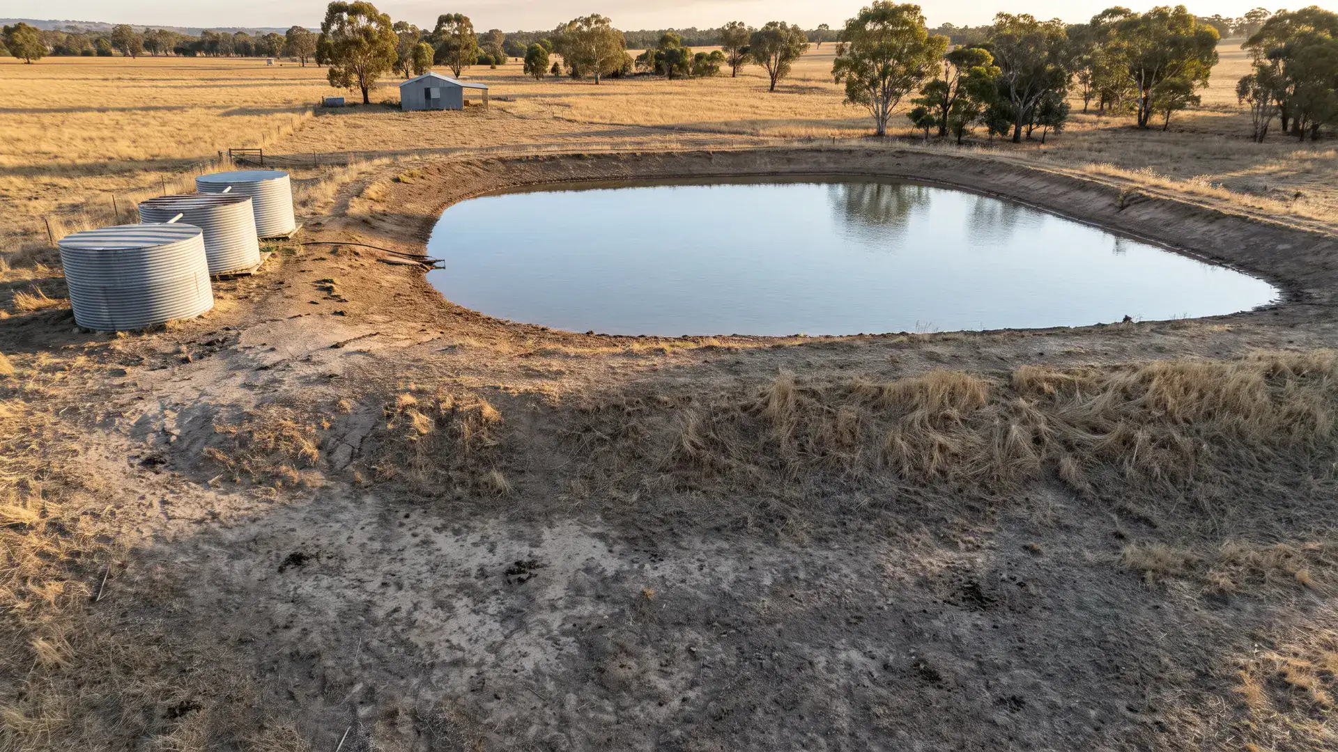 Farm dam and water tanks illustrating what is a megalitre on an Australian rural property