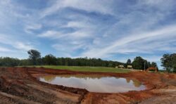 Excavation site for dam construction by Big Ditch Dam Building Company, showcasing heavy machinery.