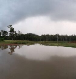 Excavation site showing dam construction by Big Ditch Dam Building Company, landscape, water, sky.
