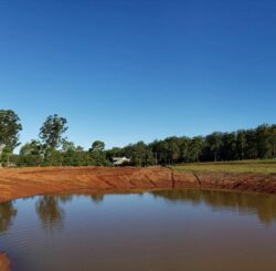 New dam construction by Big Ditch Dam Building Company with earthwork and water containment.