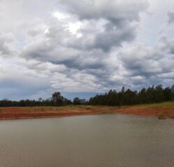 Abandoned dam construction site with water reservoir in natural landscape.