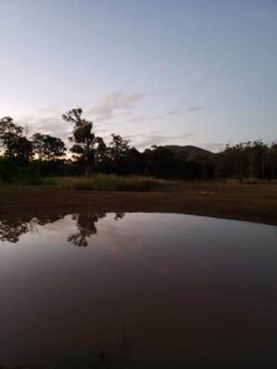 Overflow dam construction site with water reflection and natural landscape.