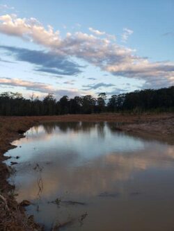 Overflow dam construction site with calm water and natural landscape.