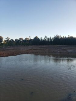 1. Dam construction site by Big Ditch Dam Building Company with water reservoir and natural surroundings.