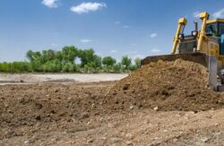 Excavator building dam at Big Ditch Dam Building Company site.