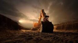 Heavy construction excavator working on dam building site at dusk, large earth-moving equipment in action.