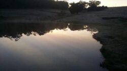 Aerial view of dam construction site with water reservoir and surrounding landscape.